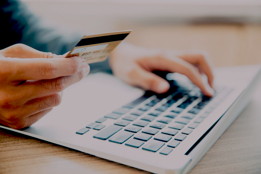 Person holding credit card in front of a laptop